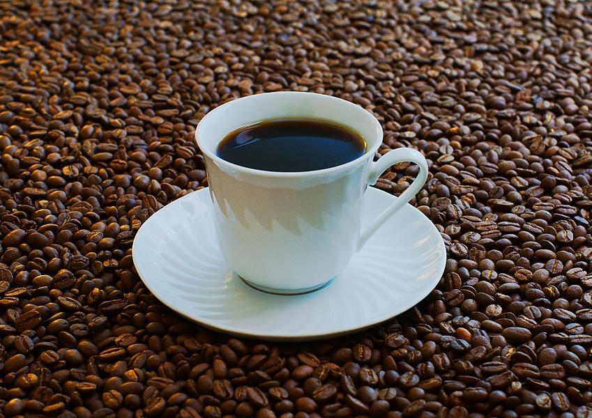 Cup of coffee surrounded by beans.jpg