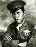 Head and shoulders of a young man wearing a peaked cap and a military jacket with ribbon bars and a badge on the left breast.
