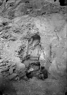 Two men work in and around an irregularly shaped pit
