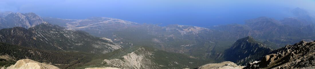 Панорама побережья с вершины горы Тахталы. Слева у побережья находятся Чамьюва и Кириш, за ними — город Кемер. Правее находится Текирова, справа вдалеке — деревня Чиралы