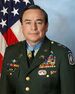A color image showing Rascon from the waist up in his military dress uniform with ribbons. His Medal of Honor is visible around his neck and an American flag is visible in the background.