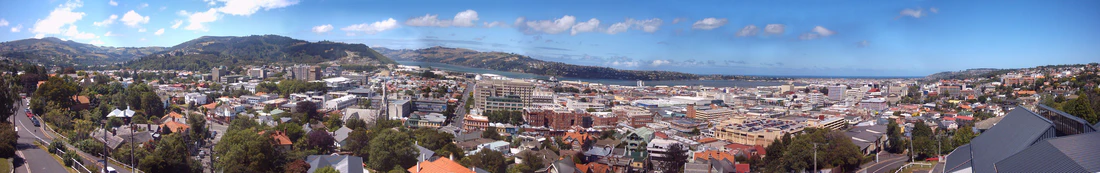 180° панорама Данидина, снятая с западных холмов. Университет изображён в левой части снимка, перед холмом