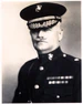 A black and white image of John Myers, a white male in his Marine Corps dress blue uniform. He has a moustache, is wearing a hat and several ribbons are visible.