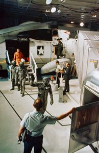 Экипаж «Аполлона-11» на борту авианосца «Хорнет» переходит из вертолёта в карантинный фургон. Впереди — Коллинз, за ним — Армстронг и Олдрин