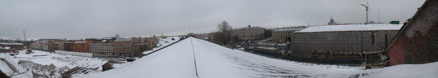 Панорама с крыши здания Новой Голландии. Слева направо: здание бывшей тюрьмы (круглое), здания вдоль набережной Адмиралтейского канала, площадь Труда, здание в лесах (пл. Труда, д. 8), над крышей которого видны Адмиралтейство (над левой частью здания) и Исаакиевский собор.