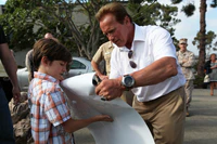 Arnold Schwarzenegger signs a young boy’s “The Expendables 2” poster, 2012.jpg