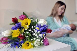 Мама с новорожденным ребенком с цветами в День матери в России.jpg